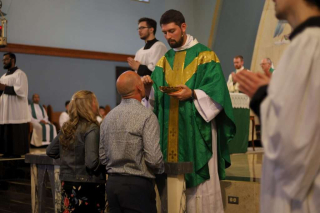 Fr. Isaac Longworth, CC distributing the Eucharist.
